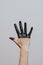 Elegant female hand dipped in black paint on a light background. Isolated. Gesture.