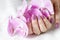 Elegant female hands with fresh pink lilac manicure with orchid flower