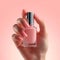 Elegant French manicure hand holds a bottle of pink polish