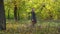 An elegant girl with a basket in a raincoat walks in the autumn forest.