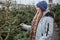 Elegant girl buys a Christmas tree. Womanin a blue cap and scarf. Beautiful lady with blond hair.