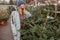 Elegant girl buys a Christmas tree. Womanin a blue cap and scarf. Beautiful lady with blond hair.