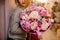 Elegant girl smiles holds a huge bouquet of different pink and purple flowers