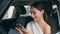 Elegant girl watching social media at smartphone on car front seat close up.