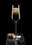 Elegant glass of yellow champagne with cork and wire cage on black marble board on black background