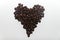 Elegant heart made of grains of roasted fragrant coffee on a white background