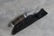 An elegant hunting knife with a scabbard and a leather handle on a concrete gray background