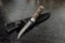 Elegant hunting knife in a sheath with a leather handle on a black textured background