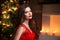 Elegant lady in red dress over christmas tree lights and candles