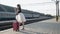 Elegant lady smiling and poses with lush skirt at suitcase on railway platform