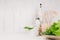 Elegant light kitchen interior with wooden utensils, ceramics and green leaves greens on white wood shelf.