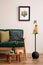 Elegant living room with mock up poster frame, bottle green sofa, black stand coffee and glass vase with leaves. Minimalist home