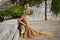 Elegant luxury evening fashion. Glamour, stylish elegant woman in long gown dress is posing in luxury hotel outdoor. Female model