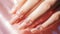 Elegant manicure on feminine hand, nail service on peach fuzz background, close-up