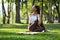 Elegant millennial woman in sportswear sitting in Half lord of the fishes pose, practicing yoga on green park with