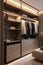 Elegant minimalist male walk in wardrobe with clothes hanging on rods, shelves and drawers.