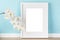 Elegant mockup template with white vertical picture frame with matte and orchid branch in front of pastel green wall