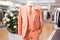Elegant monochrome men suit with peach fuzz color displayed on mannequin in contemporary boutique