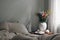 Elegant moody bedroom interior. Cup of coffee, pumpkin on retro wooden bedside table. White ceramic vase. Bouquet of