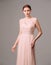 Elegant moscato dress with bow. Beautiful pink chiffon evening gown. Studio portrait of young brunette woman. Transformer dress id