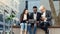 Elegant multiracial colleagues sitting on the bench near office and discussing business matters outdoors.