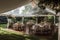 Elegant open air white tent for a wedding venue with hardwood floor and white formal furniture decor with flowers erected in a