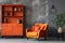 Elegant orange sofa against grey stucco wall and cabinet. Scandinavian style home interior design