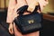 Elegant outfit. Closeup of black leather bag handbag in hand stylish woman. Fashionable girl on the street. Female
