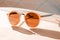 Elegant peach fuzz sunglasses with transparent sepia lenses on minimal light background. Modern trendy tone hue shade