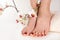 Elegant Pedicure: Young Woman\\\'s Feet with Dark Red Color Nails and Orchid Flower Decoration