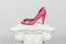 Elegant pink female high-heeled leather shoe on greek column