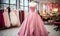 Elegant pink strapless ball gown on mannequin in a bridal boutique with various wedding dresses in the background, romantic bridal