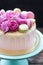 Elegant pink wedding cake decorated with melted white chocolate, beautiful fresh roses and macaroons. Black background