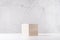 Elegant podium of beige wooden cube on white board and grey marble wall for product display. Simple modern minimalistic design.