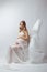 Elegant pregnant young woman standing wearing flying white fabric. Pregnancy, maternity and motherhood concept.