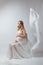 Elegant pregnant young woman standing wearing flying white fabric. Pregnancy, maternity and motherhood concept.