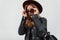 Elegant pretty young hipster woman in a vintage hat in stylish sunglasses in a fashionable black leather jacket with a backpack