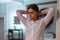 Elegant pretty young woman in a stylish white shirt straightens hairstyle in a vintage room with a mirror with bright lamps.