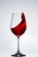 Elegant pure wineglass with wave of brightly red wine standing against light background with reflection in down.