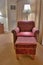 Elegant red armchair and pouffe on carpet