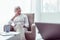 Elegant retired woman sitting in armchair standing near the window