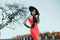 Elegant retro lady in a long red evening glamour dress. Young stylish trendy woman in a black hat with wide brim and