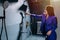 Elegant saleswoman in a purple suit testing a showerhead, water running