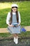 Elegant schoolgirl child girl with book in park, reading poetry concept