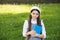 Elegant schoolgirl child girl with book in park, sophisticated schoolgirl concept