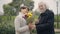 Elegant senior man waiting with bouquet of flowers as happy woman surprising husband. Happy Caucasian couple of seniors
