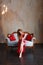 Elegant sensual young redhair woman in red dress sitting on classic sofa and looking at camera. Loft interior with bulb