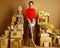 Elegant shopper woman among 2 piles of golden gifts