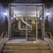 An elegant sixties apartment building`s main entrance, with marble stairs and a framed glass door