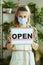 Elegant small business owner woman in apron showing open sign